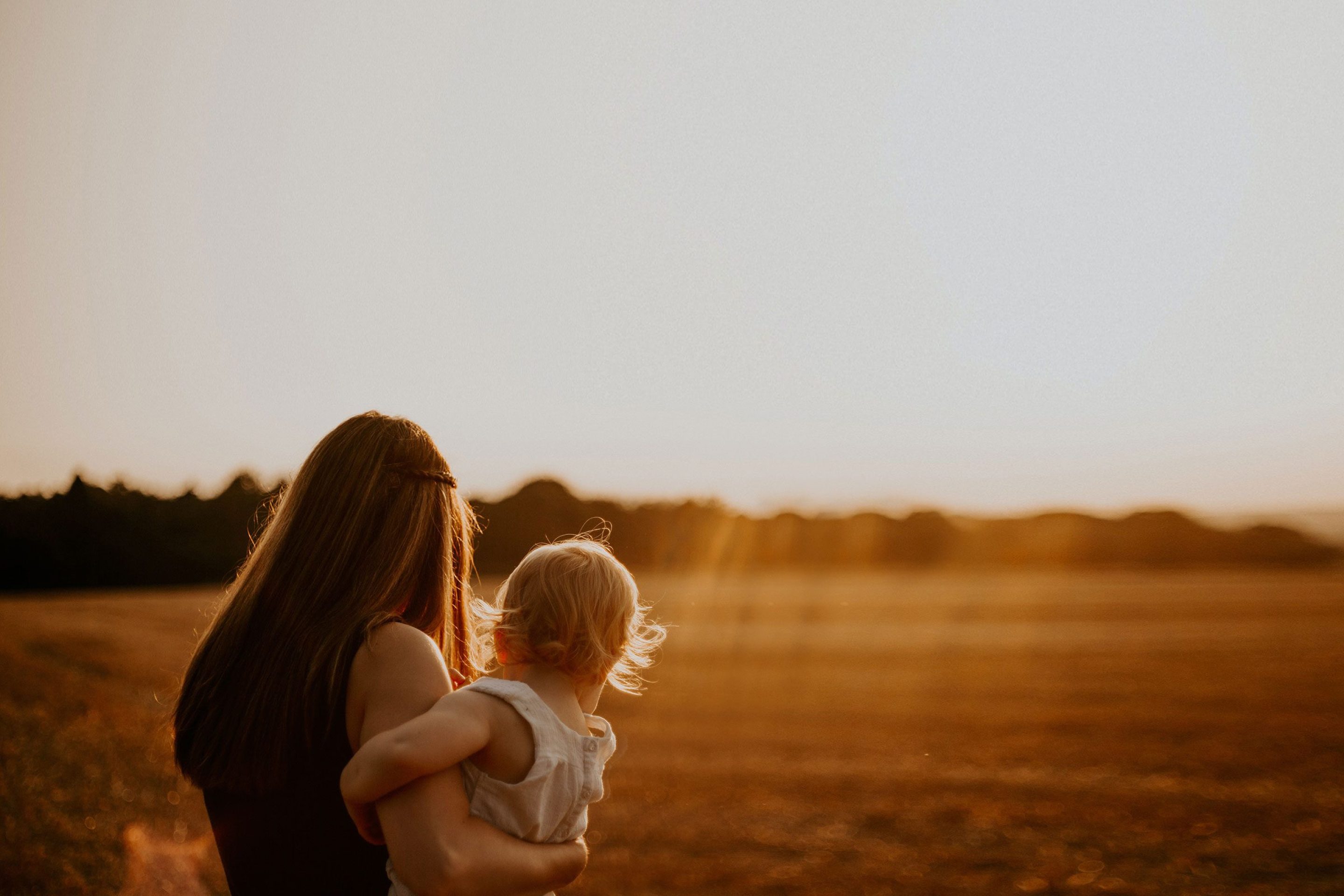 mother holding her daughter looking at the sunset